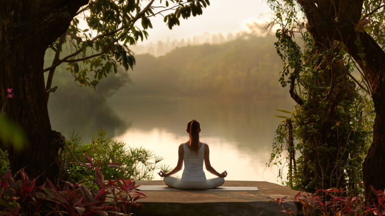 A woman is sitting by the Swan Lake Lawn, Wellness Resort Khao Yai