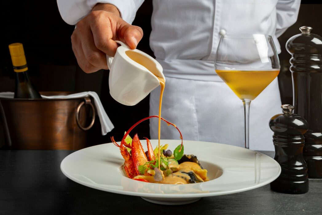 chef pouring sauce over a high-end dinner plate
