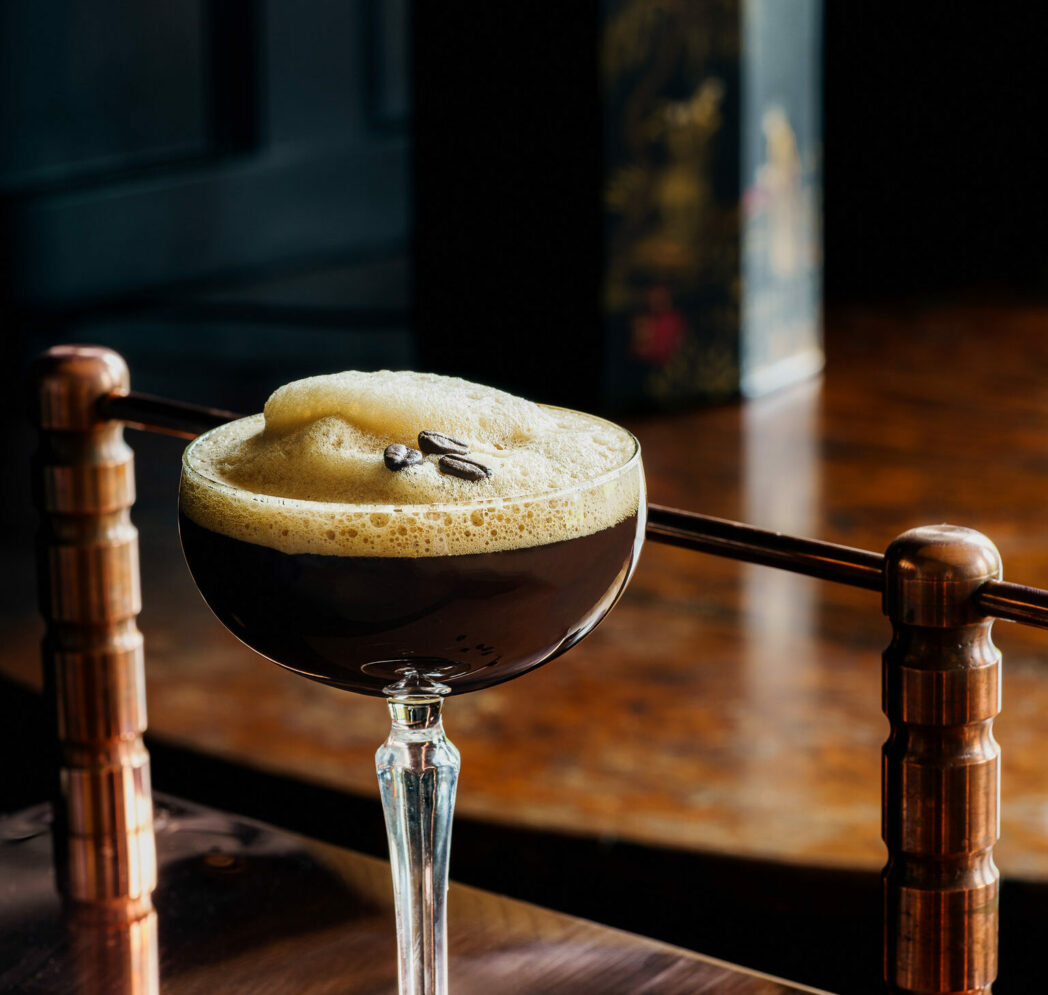 a high end cocktail topped with foam and a few coffee beans
