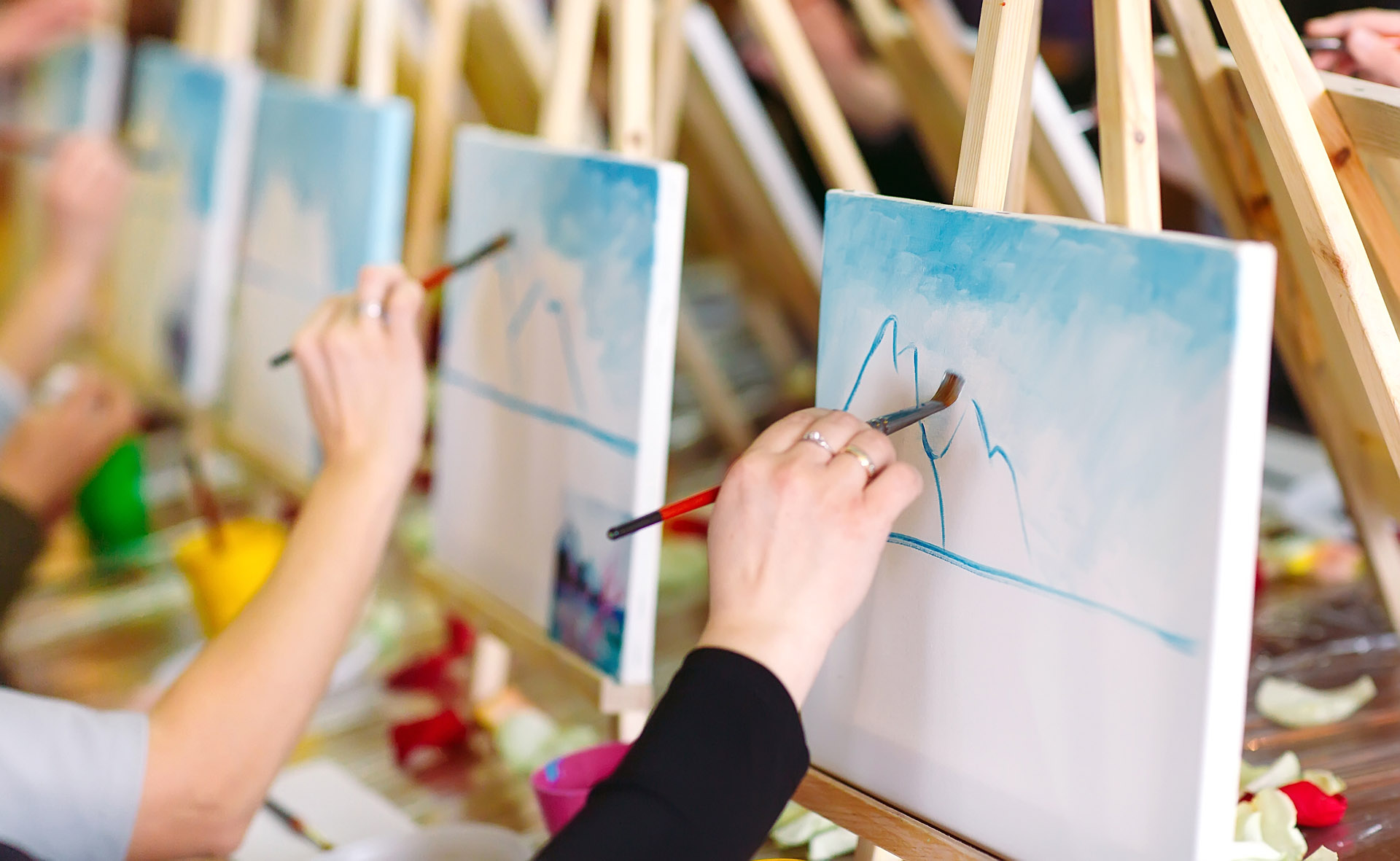artists practicing brushstrokes on a row of easels