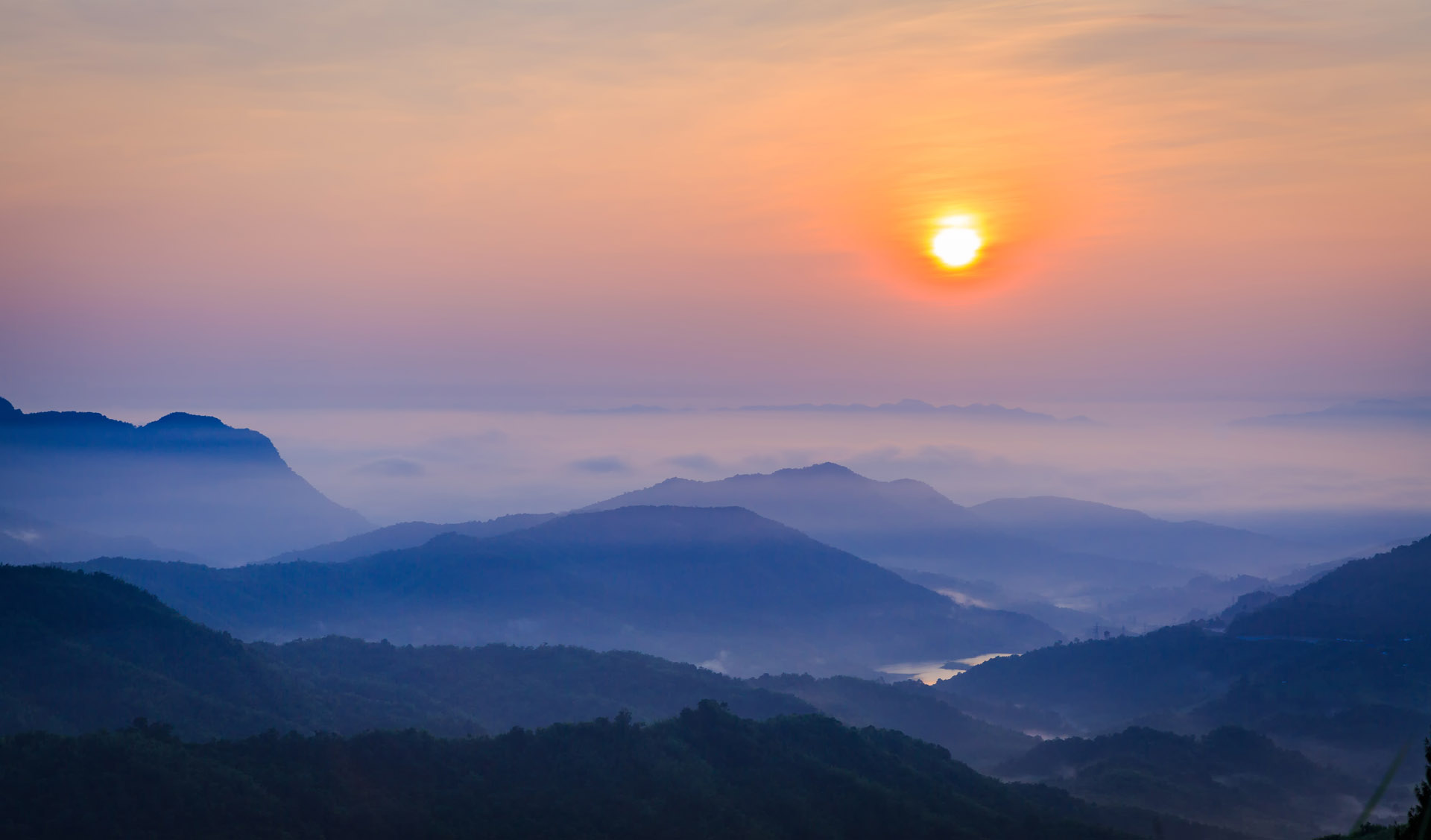 พระอาทิตย์ขึ้นเหนือภูเขาสีฟ้าและท้องฟ้าสีม่วงใน ประเทศไทย